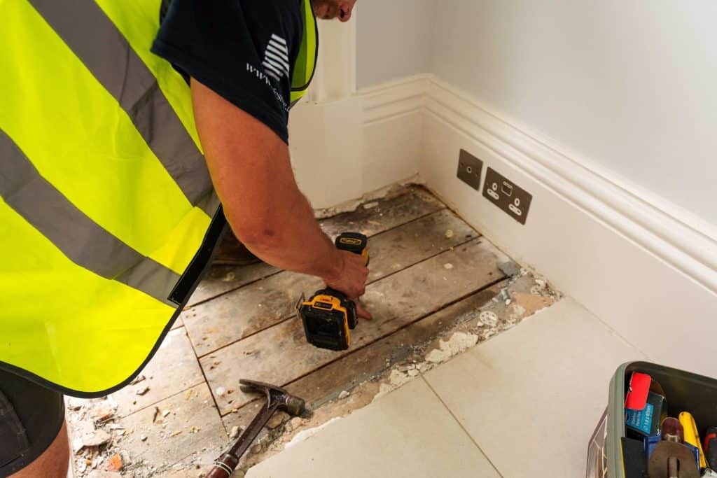 technician using power tools to fix flooring in a residential property