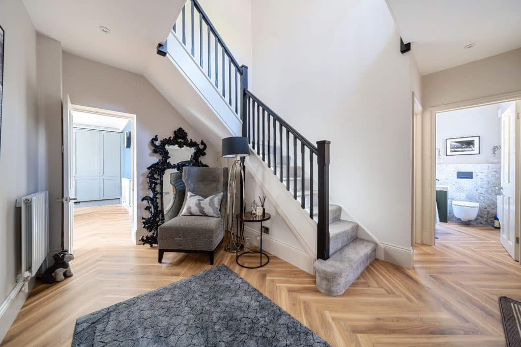 hallway and staircase, with a grey rug on the floor and a grey chair in the corner.