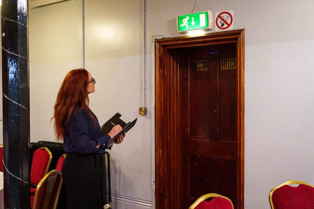 health and safety advisor asssesing and testing the functionalities of the building. looking and making sure that the lighting is working and fire doors
